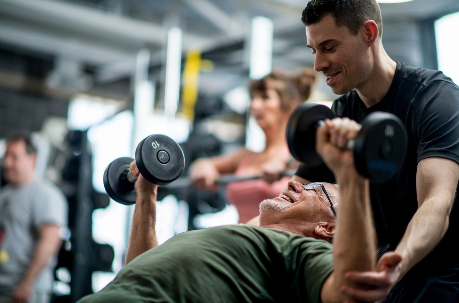 Personal trainer coaching a beginner client through a dumbbell press at Momentum Fitness on the Upper West Side