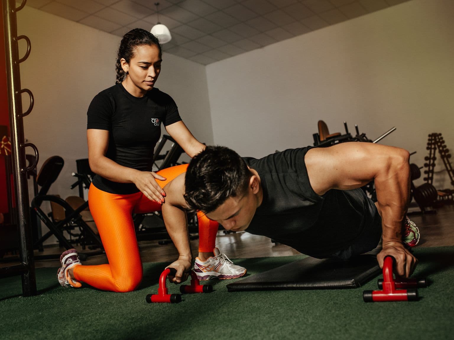 Personal trainer coaching a client through parallette push-ups at a bodyweight training gym in NYC